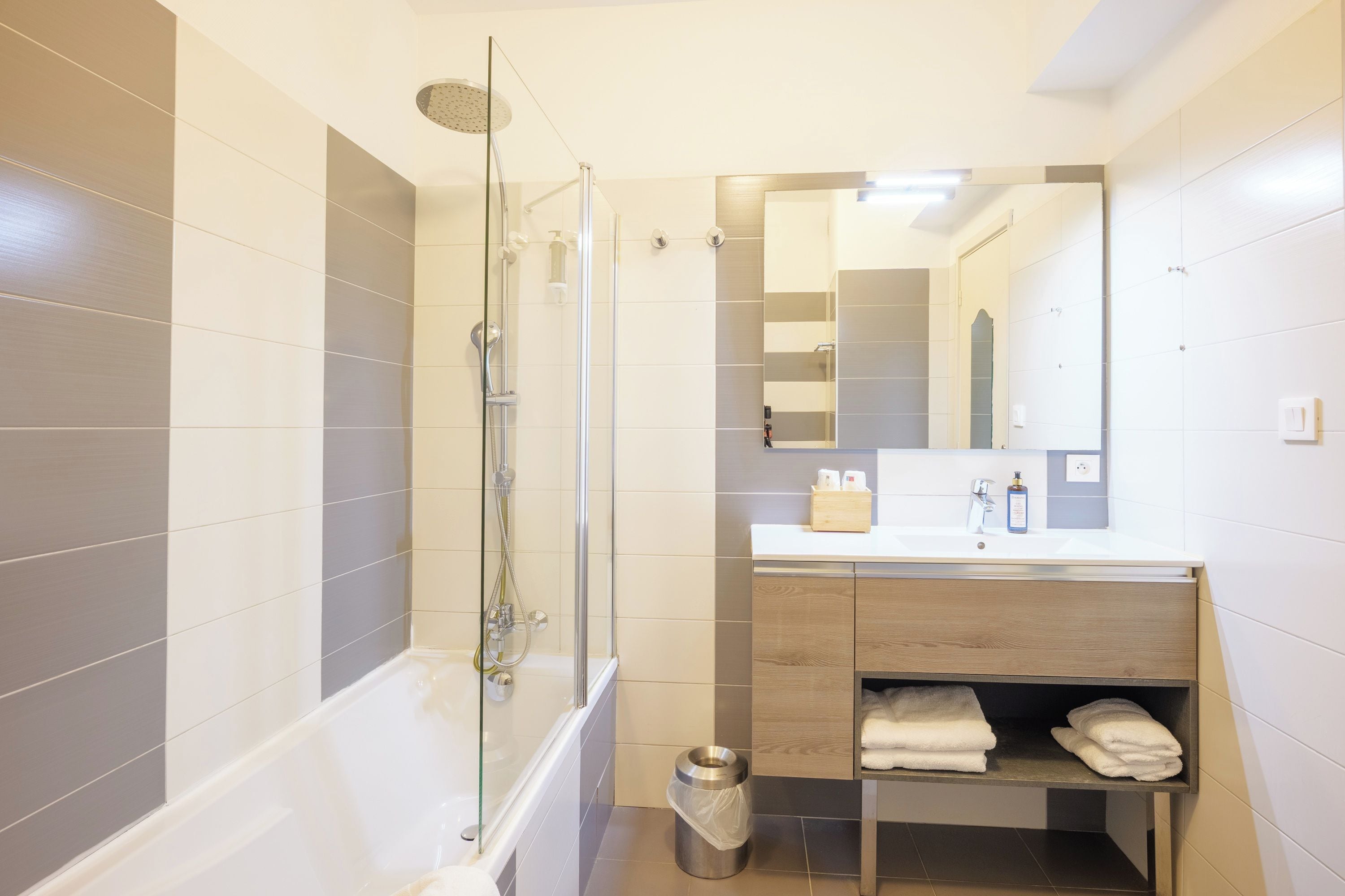 A modern bathroom with a glass-enclosed shower, a vanity with a mirror, and a towel rack.