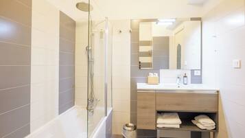 A modern bathroom with a glass-enclosed shower, a vanity with a mirror, and a towel rack.