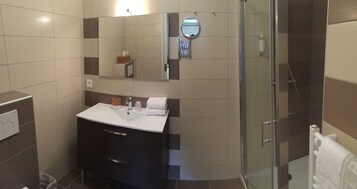 A modern bathroom with a glass shower enclosure, a vanity with a mirror, and a towel rack.