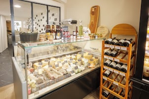 Una exhibición de quesos y vinos en una tienda, con varias variedades de queso y botellas de vino en estantes.