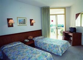 Habitación de hotel con dos camas, un escritorio, un televisor y una ventana con vistas.