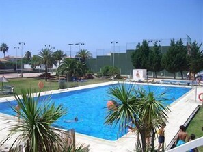 A swimming pool with palm trees and a clear sky. - Daurada Park (Cambrils)