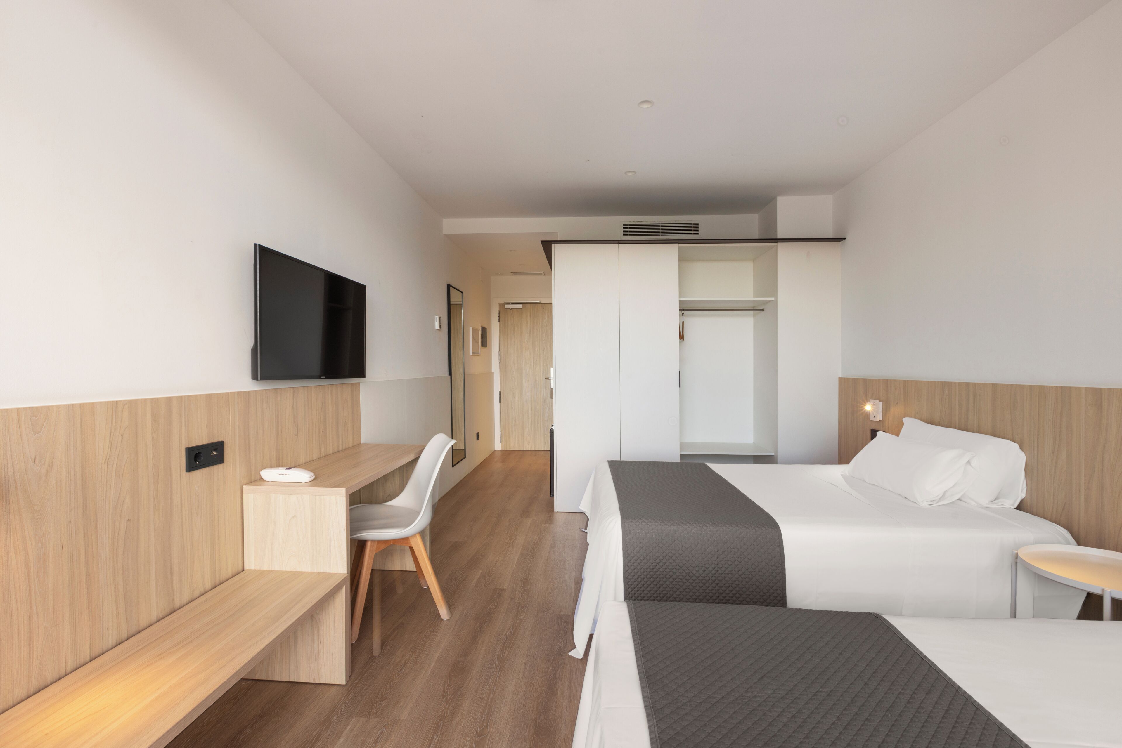 Una habitación de hotel moderna con cama, escritorio, silla y televisor.