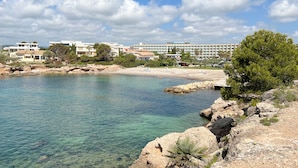 A coastal view with clear water, rocky shoreline, and buildings in the background. - RVHotels Ametlla Mar (L'Ametlla de Mar)