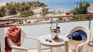 A balcony with a table, a chair, a bottle of champagne, and a basket of sunglasses. - RVHotels Ametlla Mar (L'Ametlla de Mar)