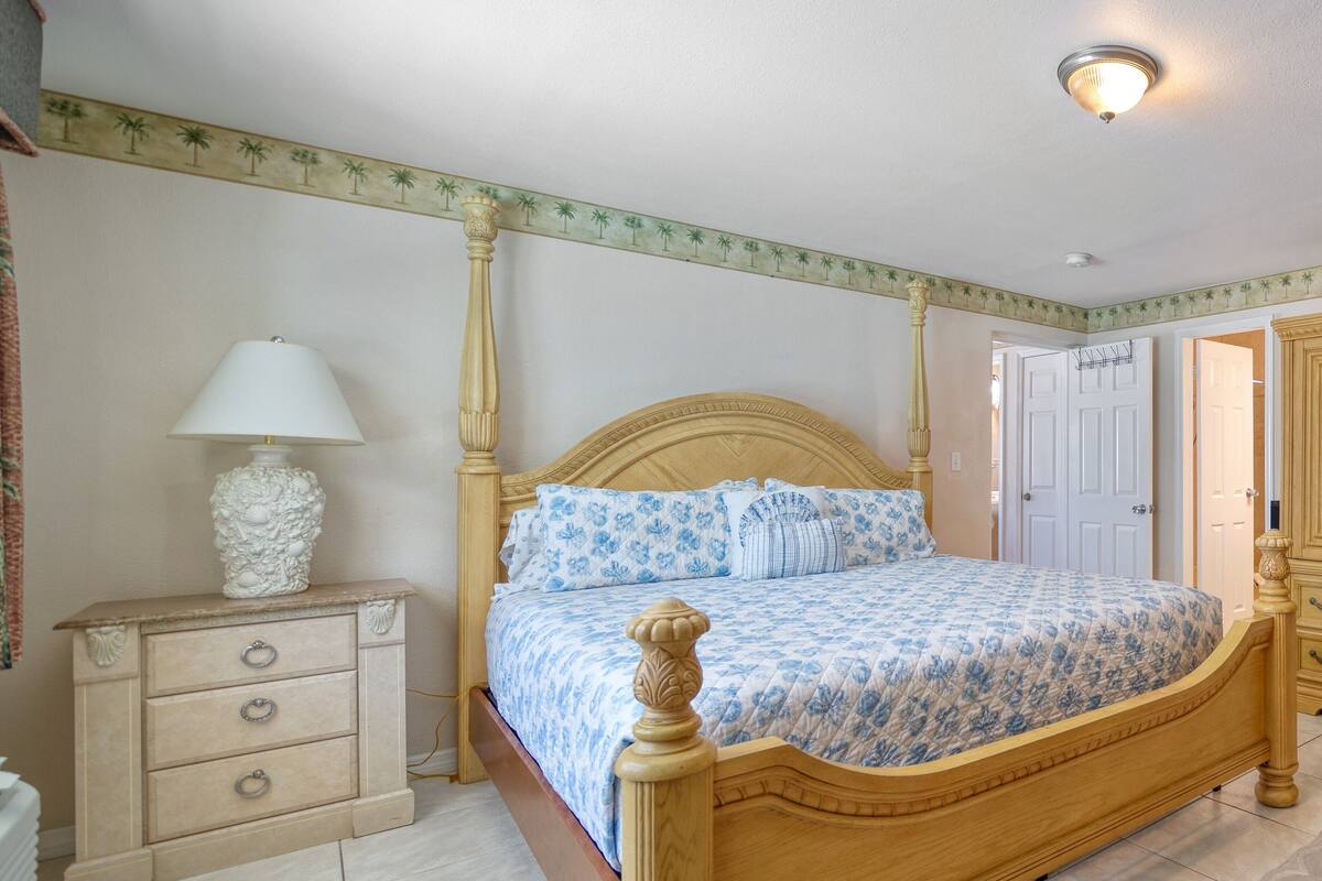 Ein Schlafzimmer mit einem hölzernen Himmelbett, einem Nachttisch mit Lampe und einer Kommode mit Schubladen.