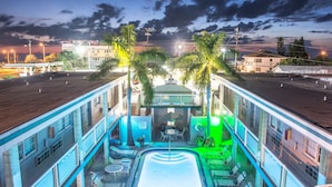A rooftop pool area with lounge chairs, a pool table, and palm trees. - Camelot Beach Suites (Clearwater Beach)