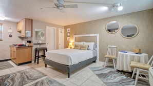 A bedroom with a bed, bedside tables, a desk, and a chair. - Camelot Beach Suites (Clearwater Beach)