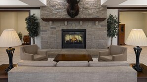 A lobby with a stone fireplace, two sofas, a coffee table, and two lamps.