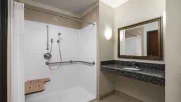 A bathroom with a shower, a sink, a mirror, and a towel rack.