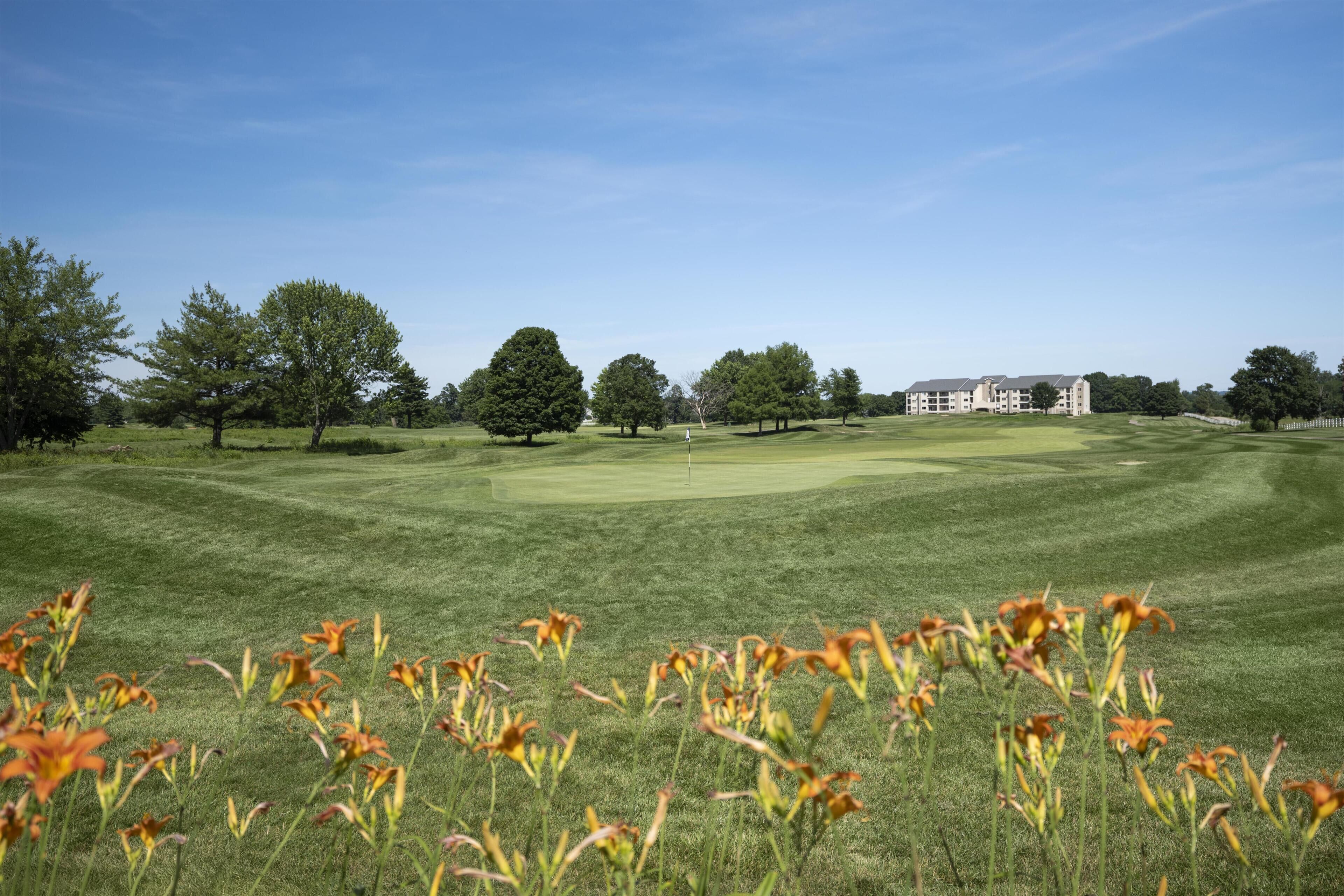 Un campo de golf con un club de campo al fondo.