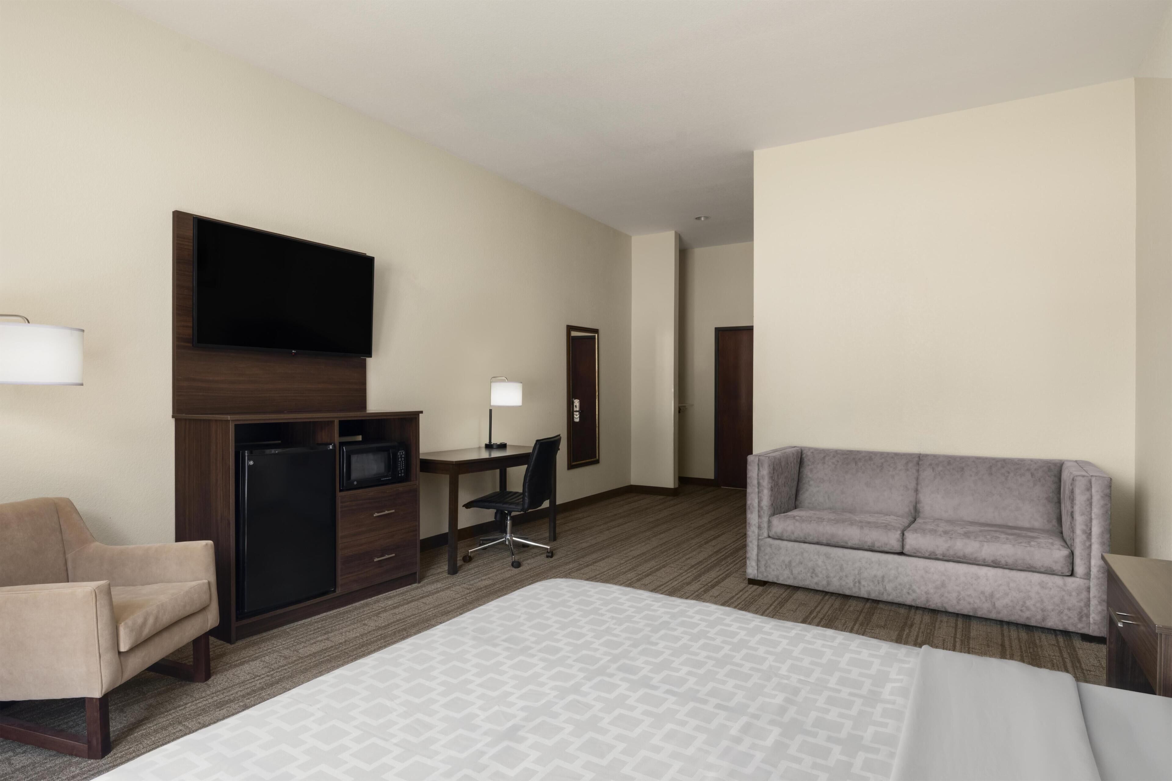 Une chambre d’hôtel équipée d’un lit, d’un bureau, d’une chaise, d’un canapé et d’une télévision.