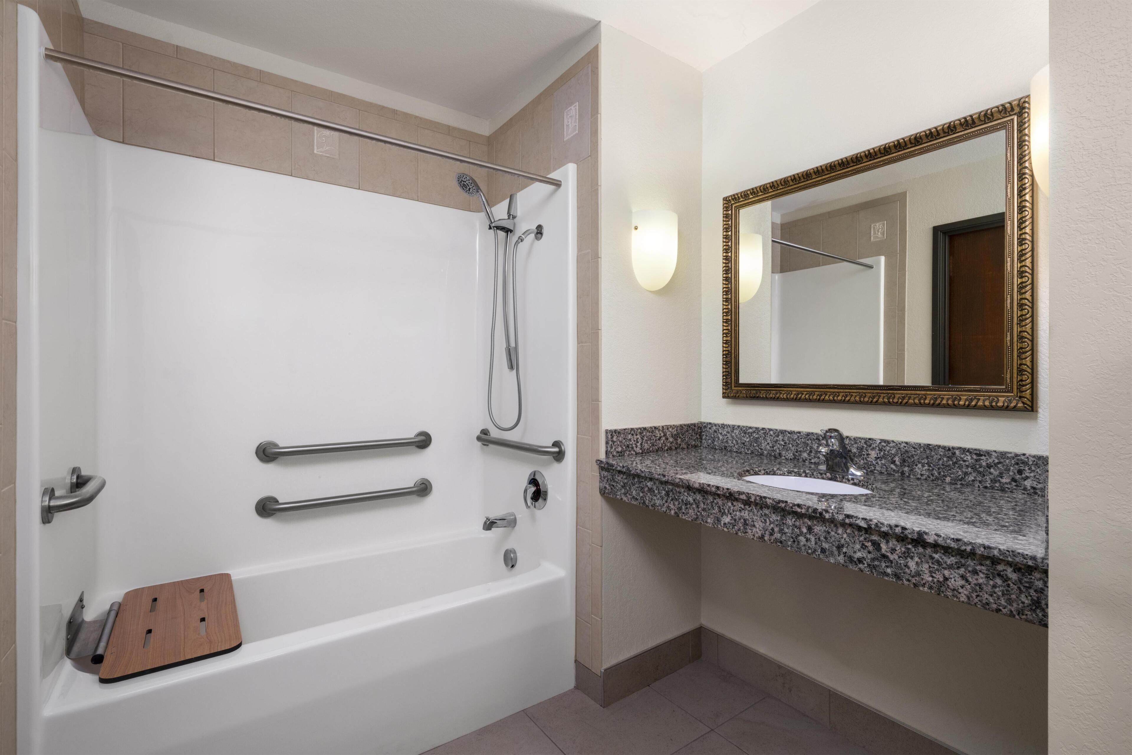 A bathroom with a bathtub, a shower, a sink, and a mirror.
