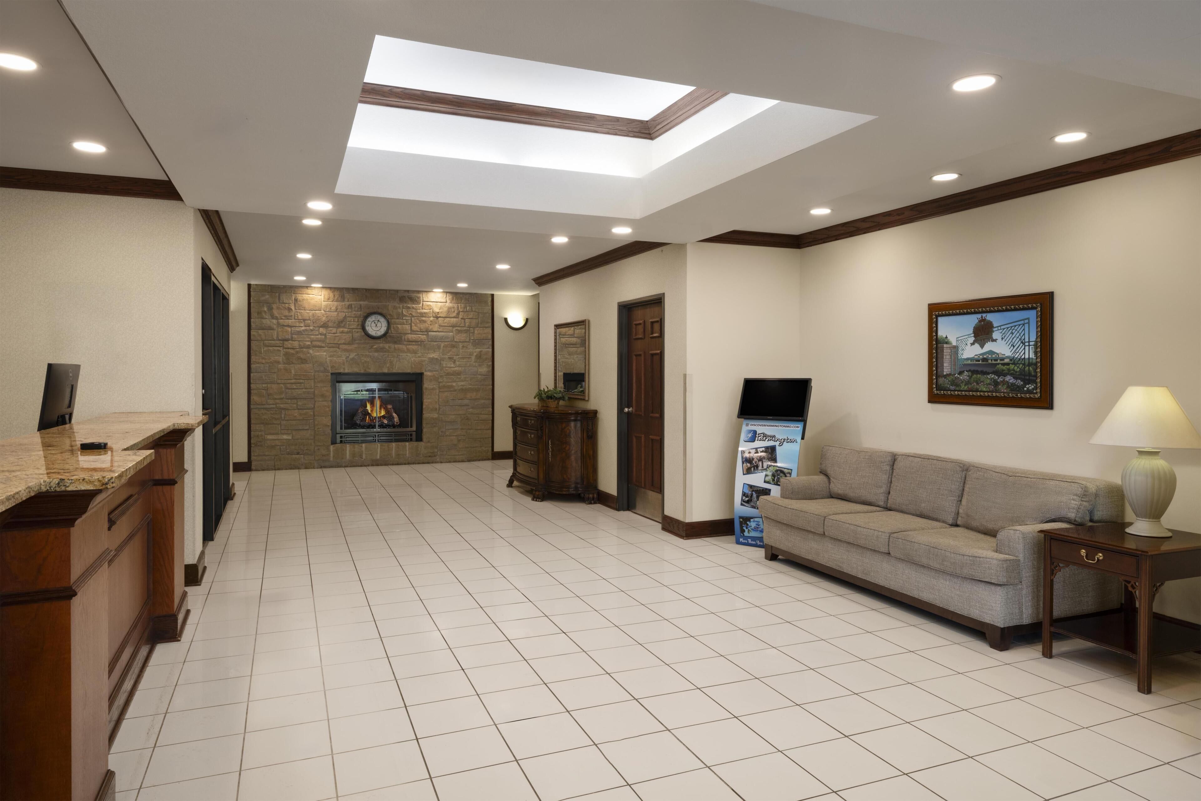 A spacious lobby with a fireplace, a sofa, and a reception desk.
