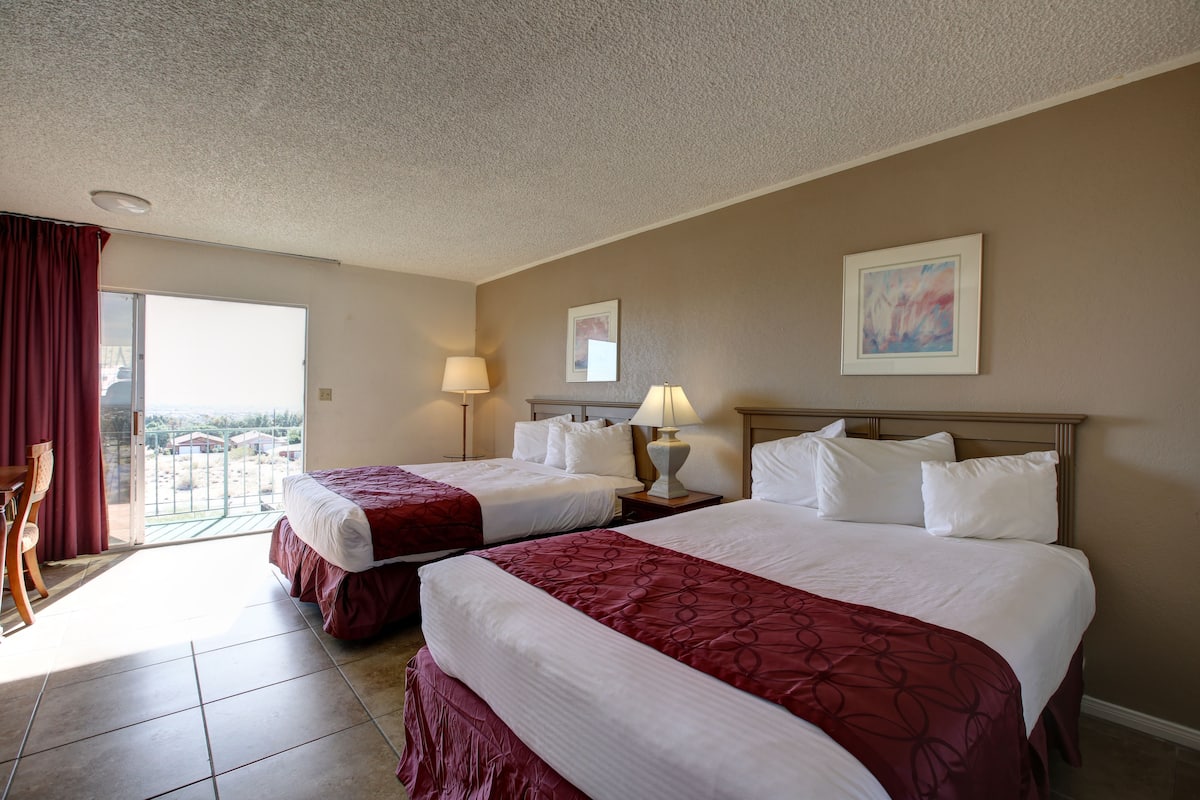 A hotel room with two beds, a balcony, and a view of the city.