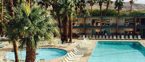 A pool area with multiple swimming pools, lounge chairs, and palm trees.