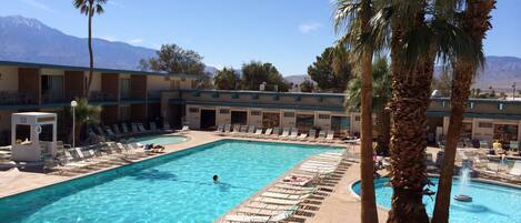 A pool area with lounge chairs, palm trees, and a lifeguard stand.