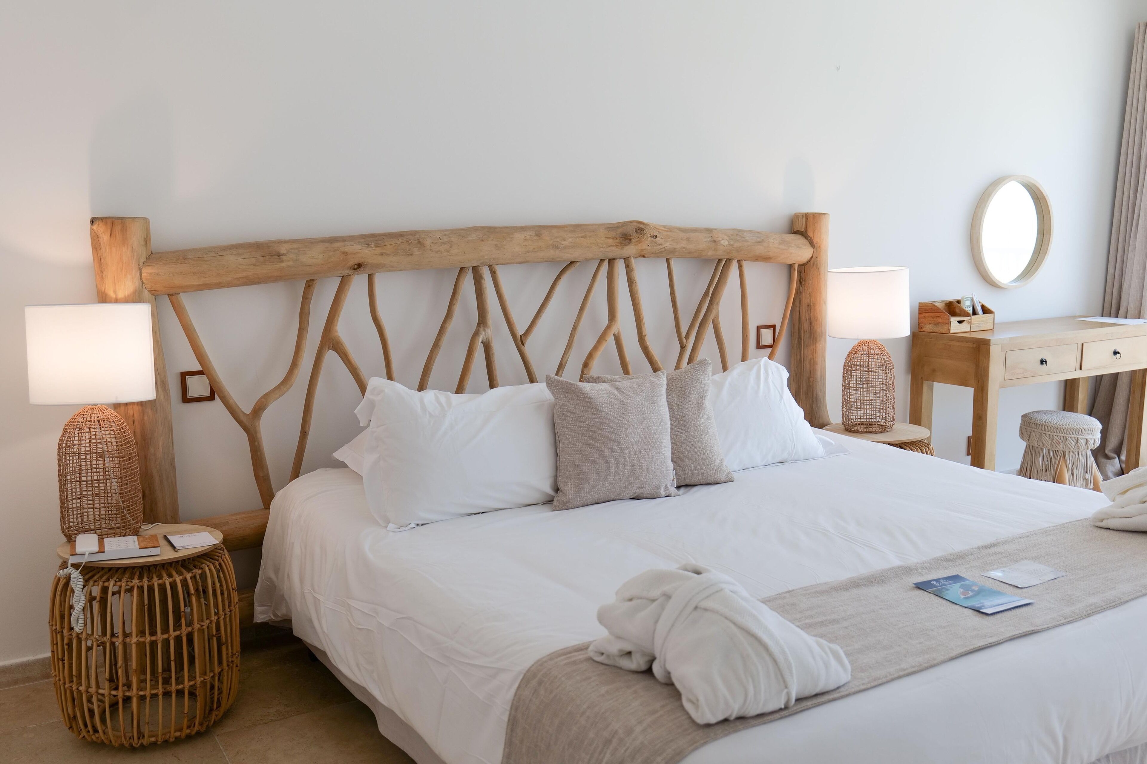 A neatly made bed with white linens, a wooden headboard, and a bedside table with a lamp.