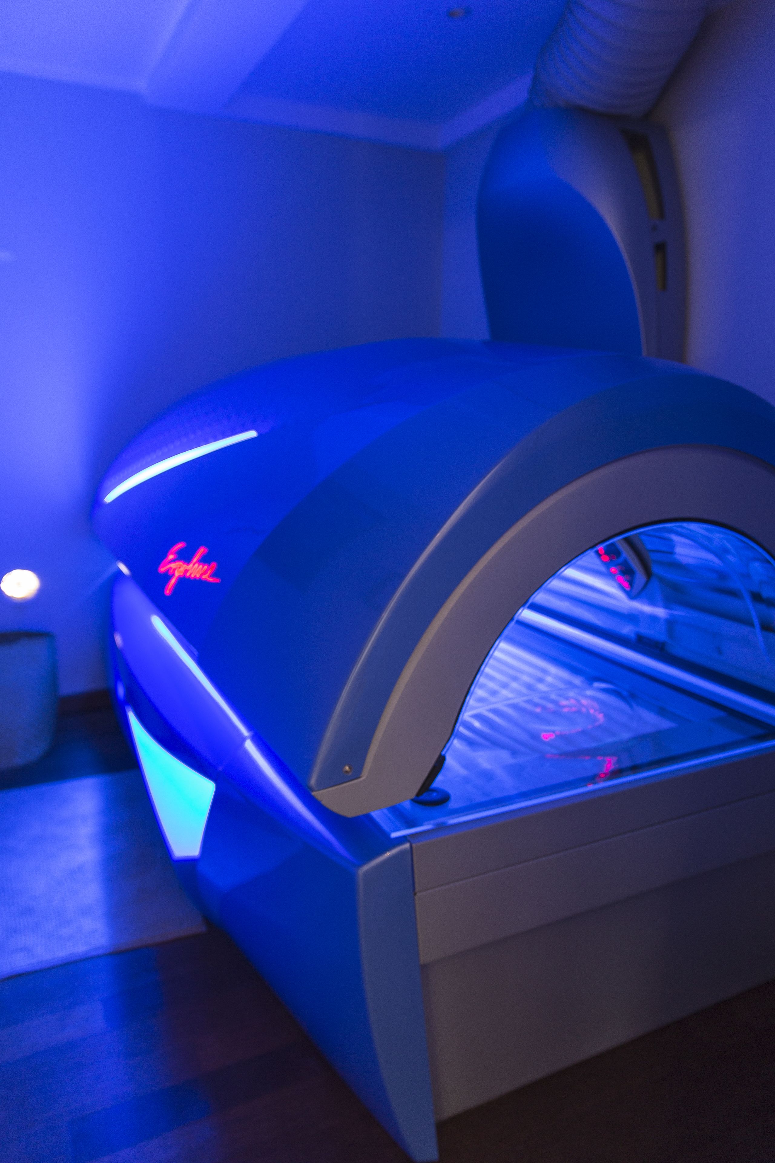 A massage chair with a curved design and a neon sign.