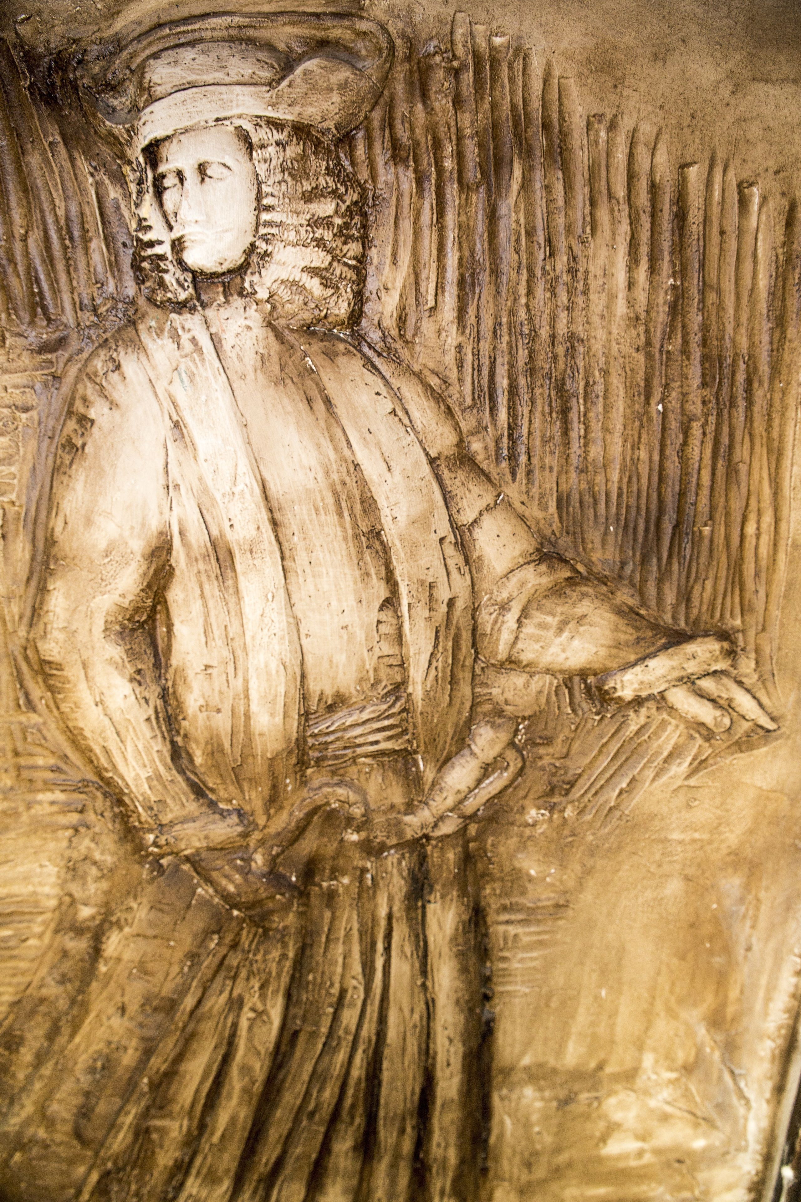 A detailed sculpture of a figure with a hat and a flowing garment.