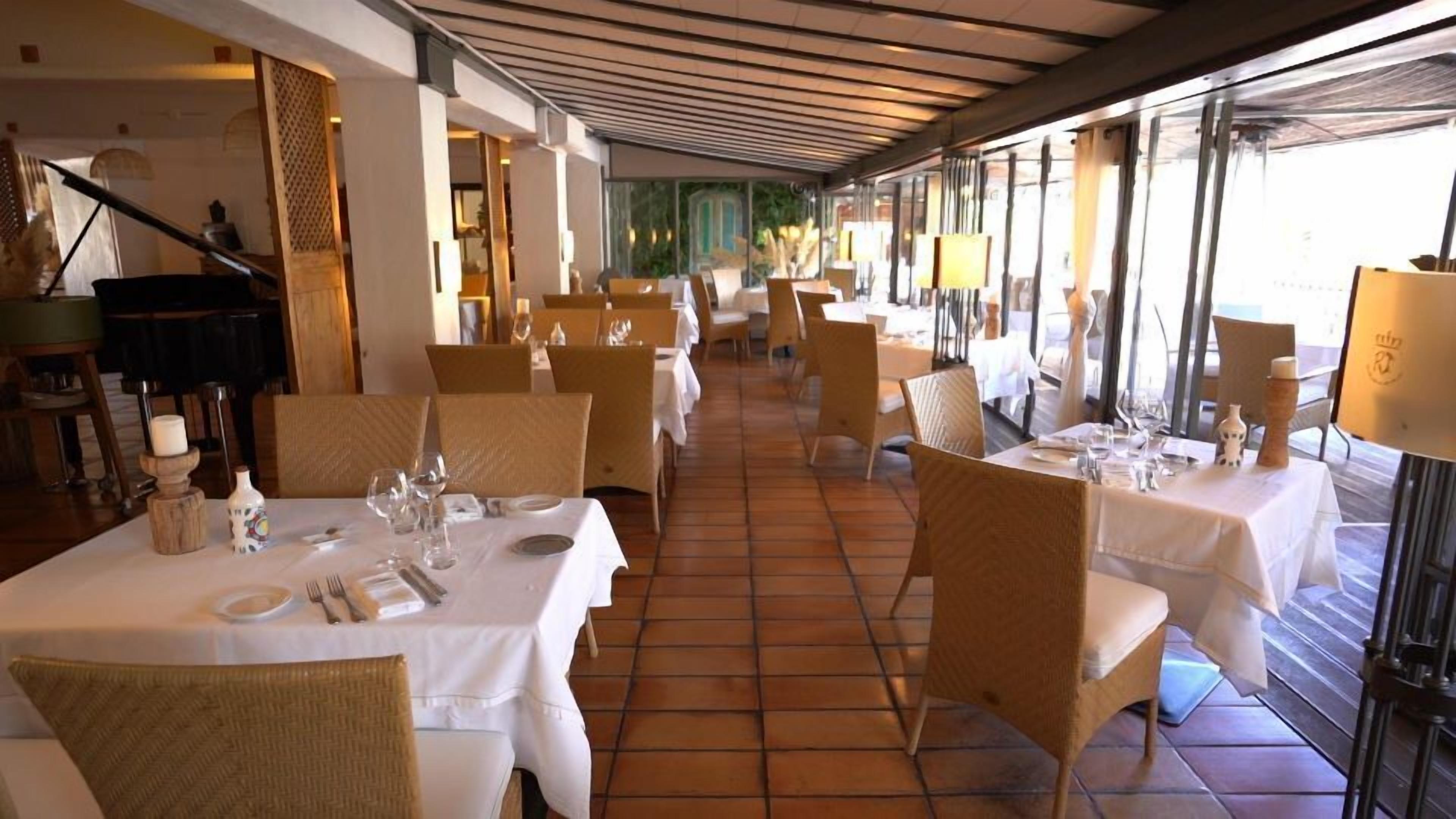 Een restaurant met gedekte tafels, stoelen en een betegelde vloer.