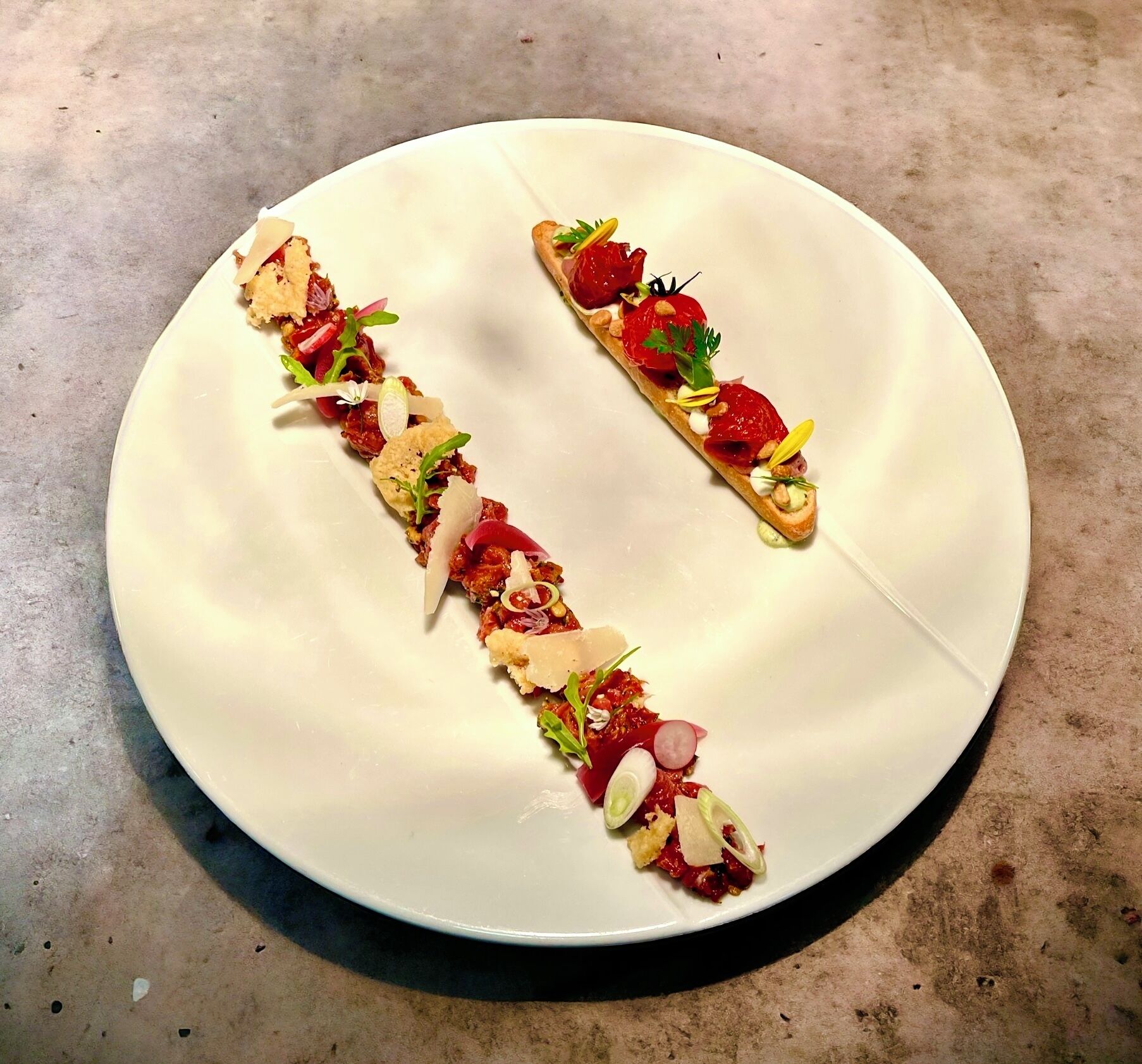 Un plato blanco con dos porciones de comida dispuestas en forma de 'T'.