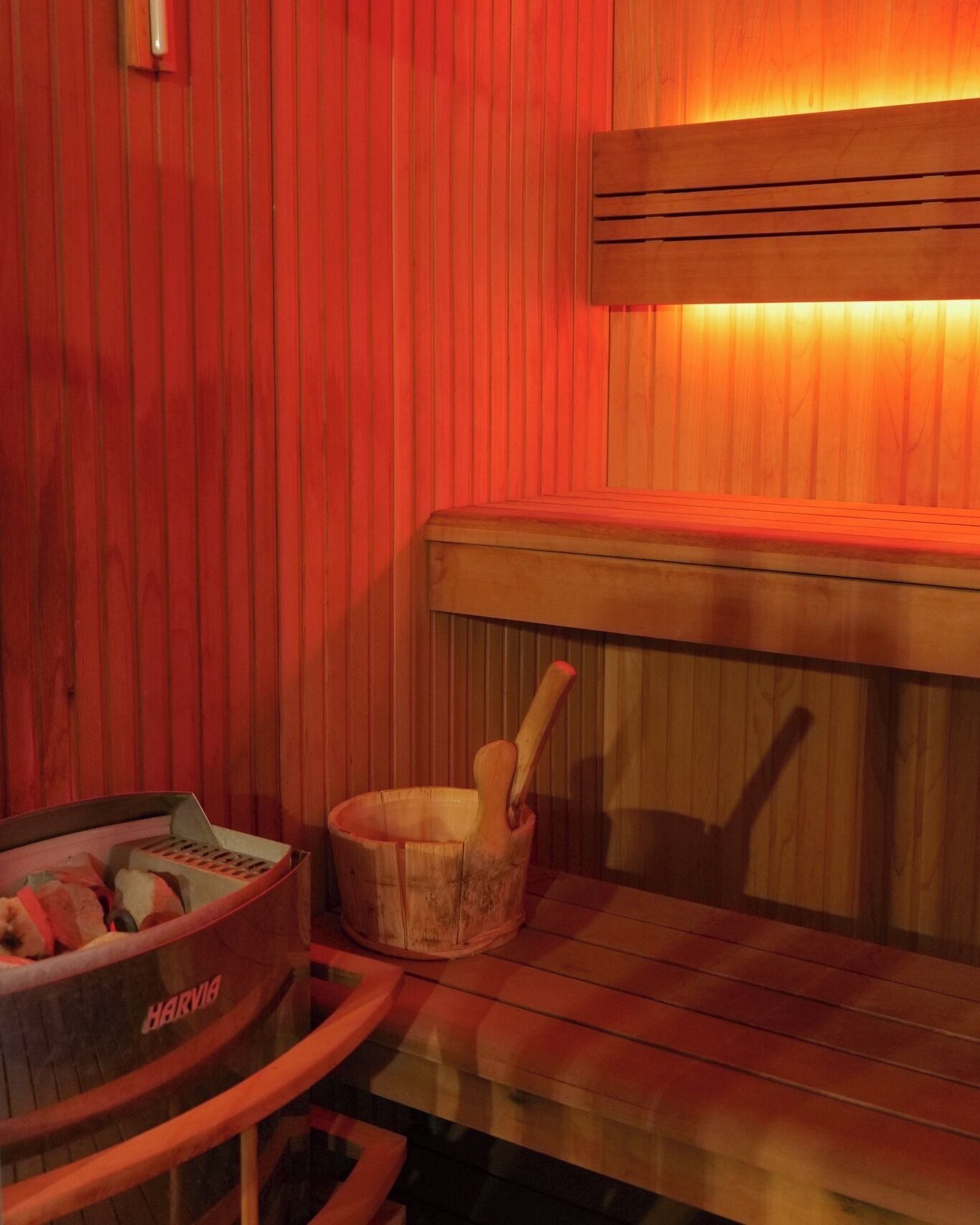 A sauna room with wooden benches and a wooden bucket with a ladle.