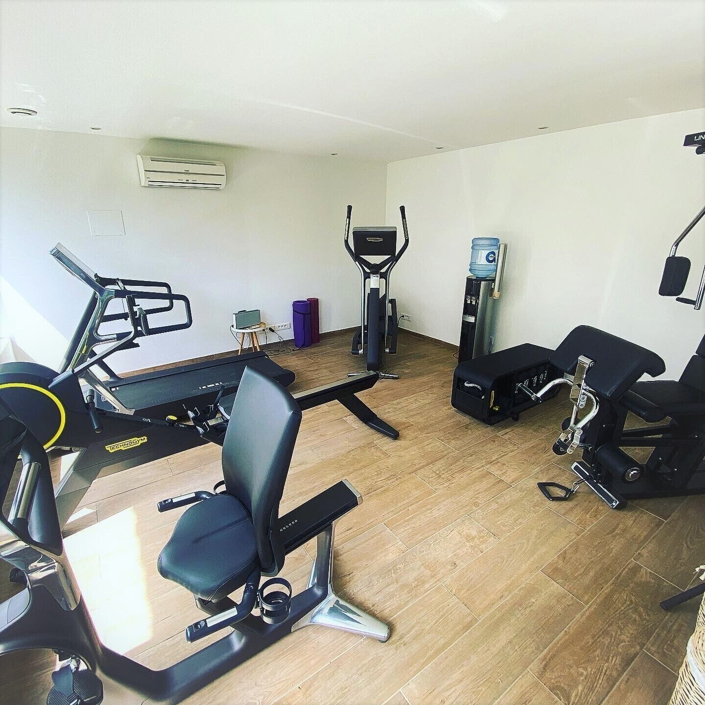Une salle de sport équipée d’un tapis de course, d’un vélo elliptique, d’un vélo d’appartement et d’un banc de musculation.