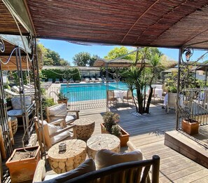 A covered outdoor area with a pool, lounge chairs, and wooden tables. - Le Roi Théodore (Porto-Vecchio)
