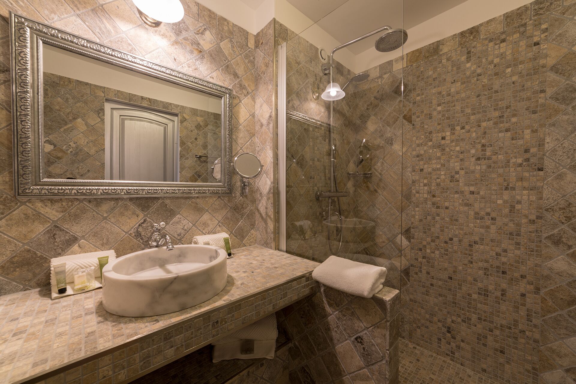A bathroom with a marble sink, a large mirror, and a shower with a glass door.