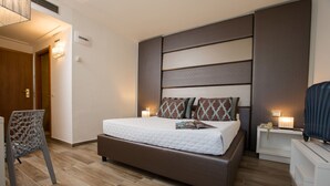 Ein modernes Schlafzimmer mit einem großen Bett, einem Nachttisch, einem Sessel und einem Fernseher.