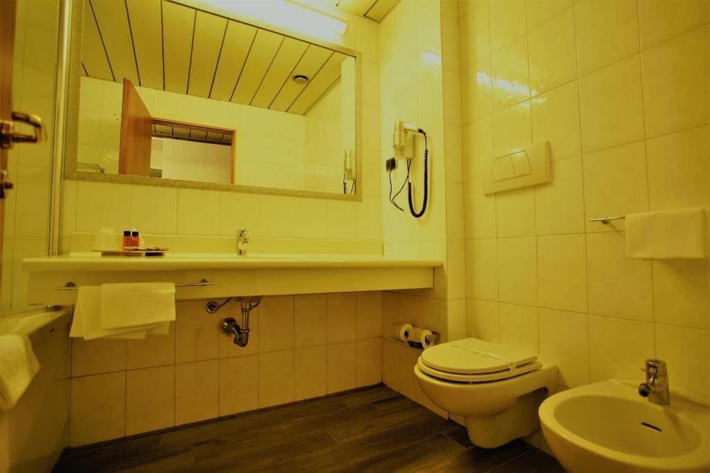 A bathroom with a toilet, bidet, sink, and mirror.