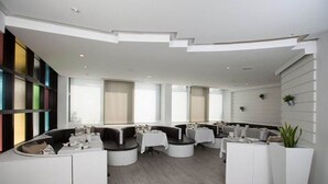Eine moderne Hotelhalle mit einer gebogenen Rezeption, Sitzbereichen und großen Fenstern.