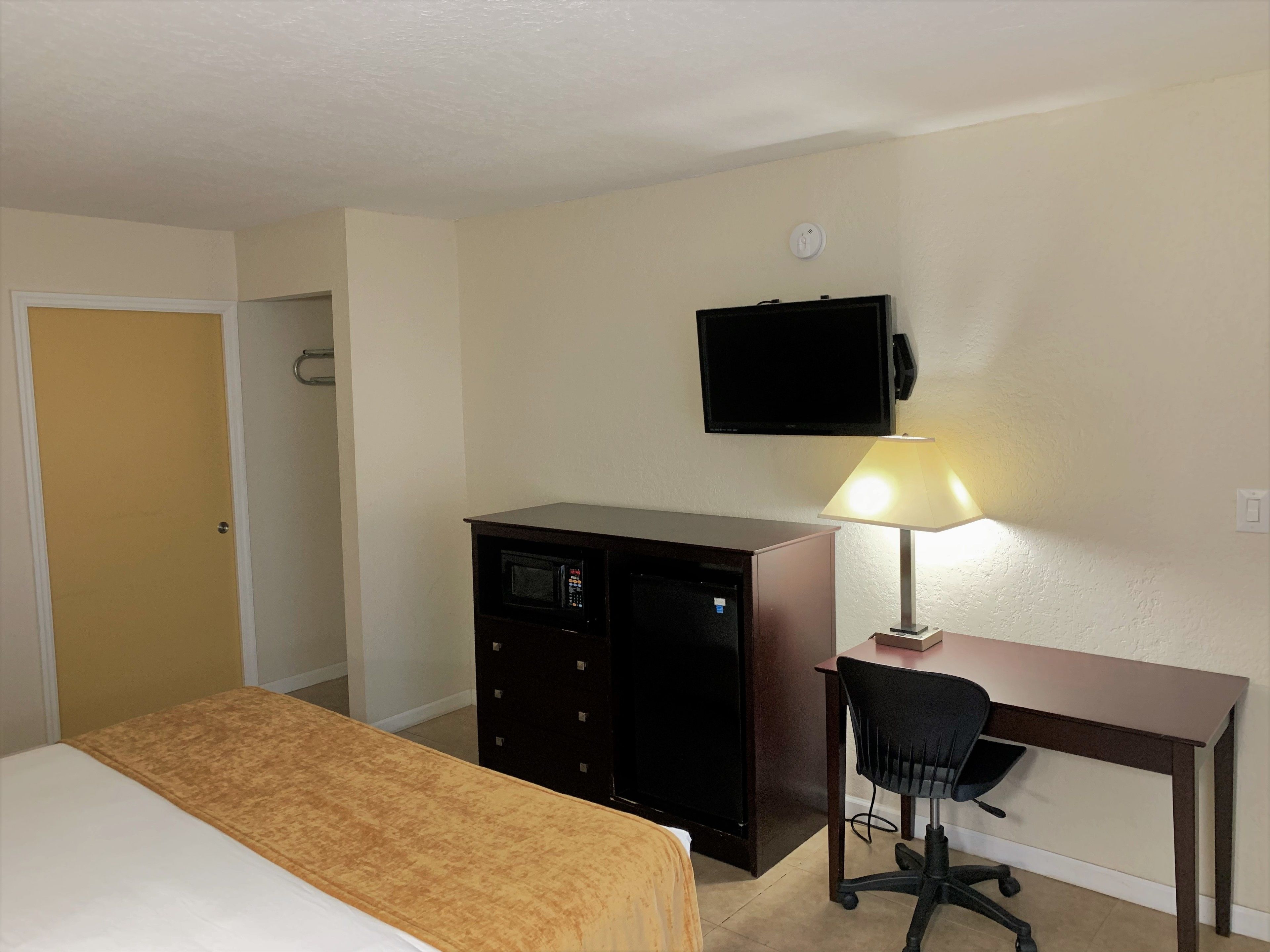 Une chambre d’hôtel équipée d’un lit, d’un bureau, d’une chaise, d’une télévision et d’une lampe.