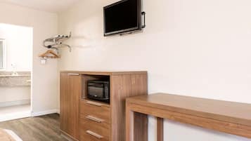 Una kitchenette con microondas, armarios de madera y un televisor montado en la pared.