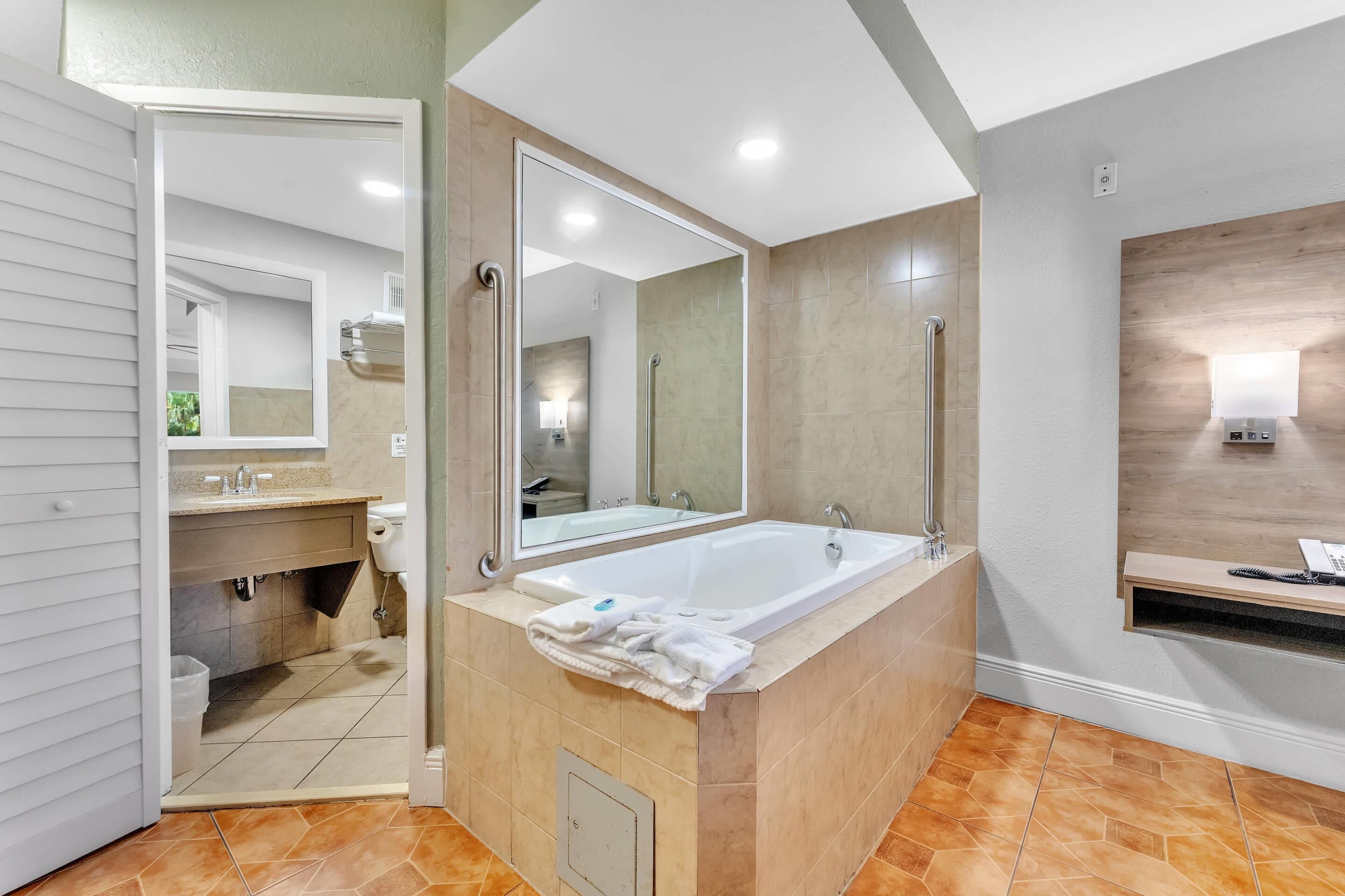 A modern bathroom with a large bathtub, a vanity with a mirror, and a shower area.