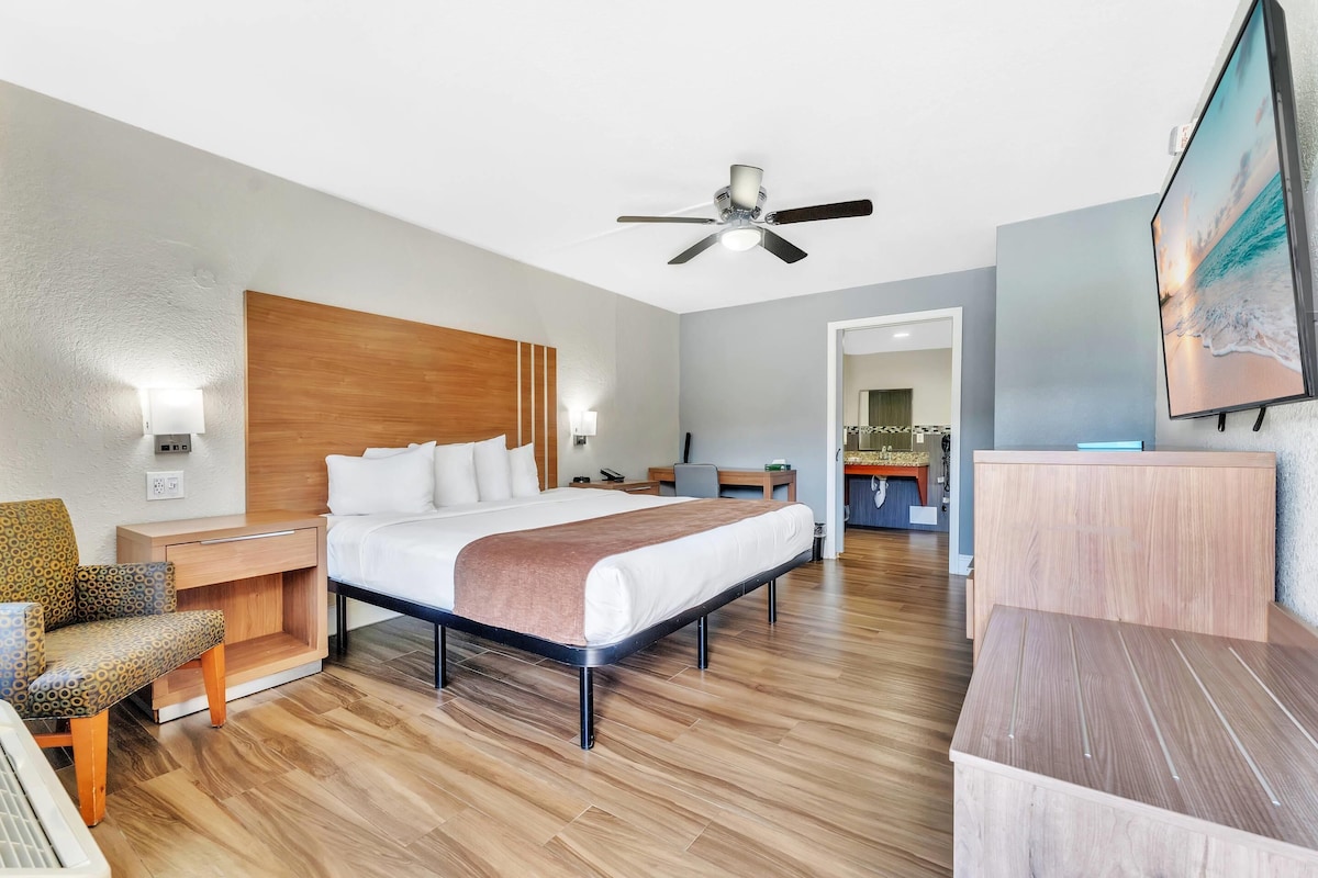 Een moderne hotelkamer met een groot bed, een bureau, een stoel, een plafondventilator en een televisie aan de muur.