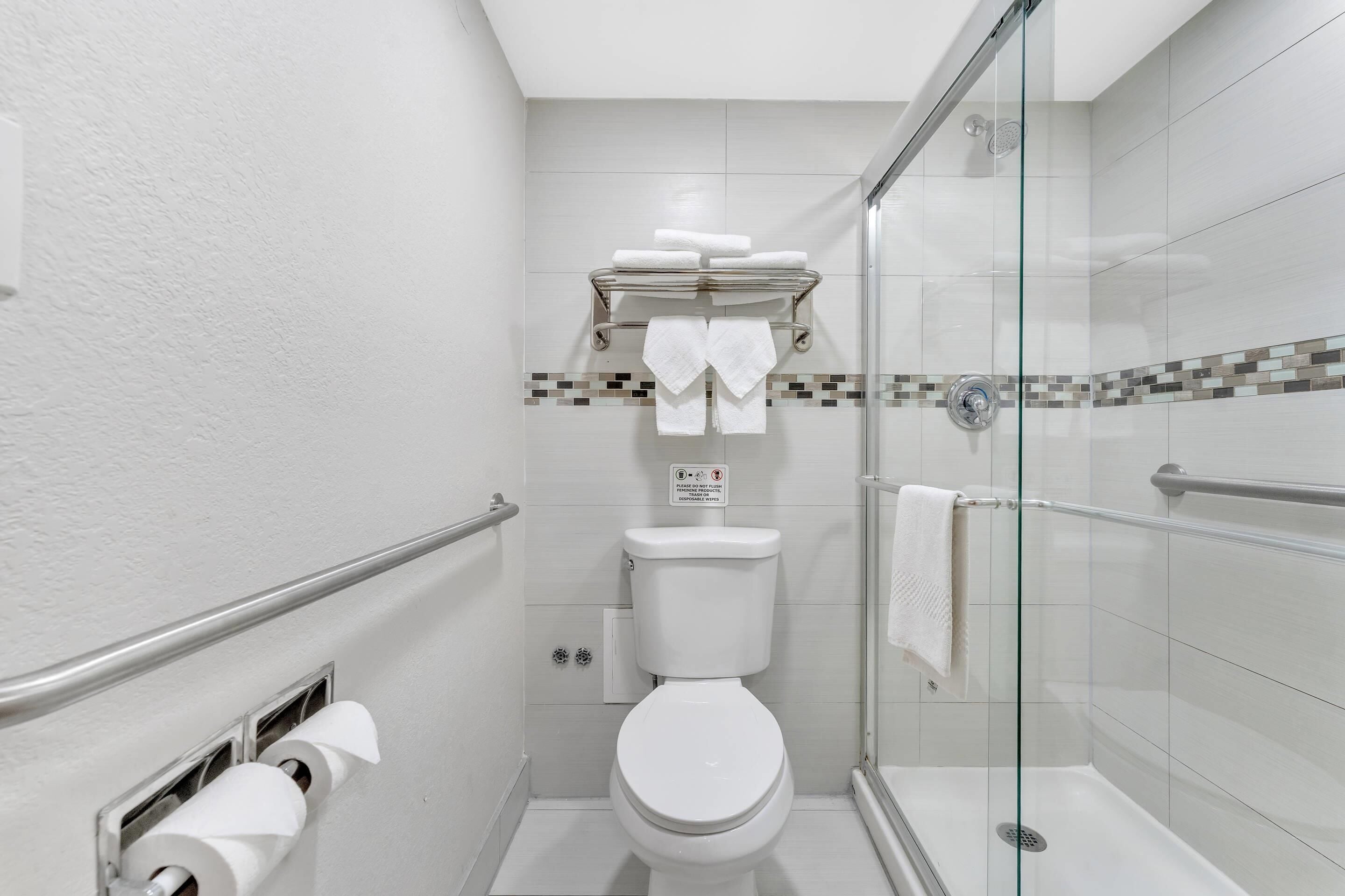 A modern bathroom with a toilet, a glass shower enclosure, and a towel rack.