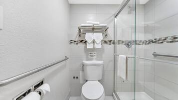 A modern bathroom with a toilet, a glass shower enclosure, and a towel rack.