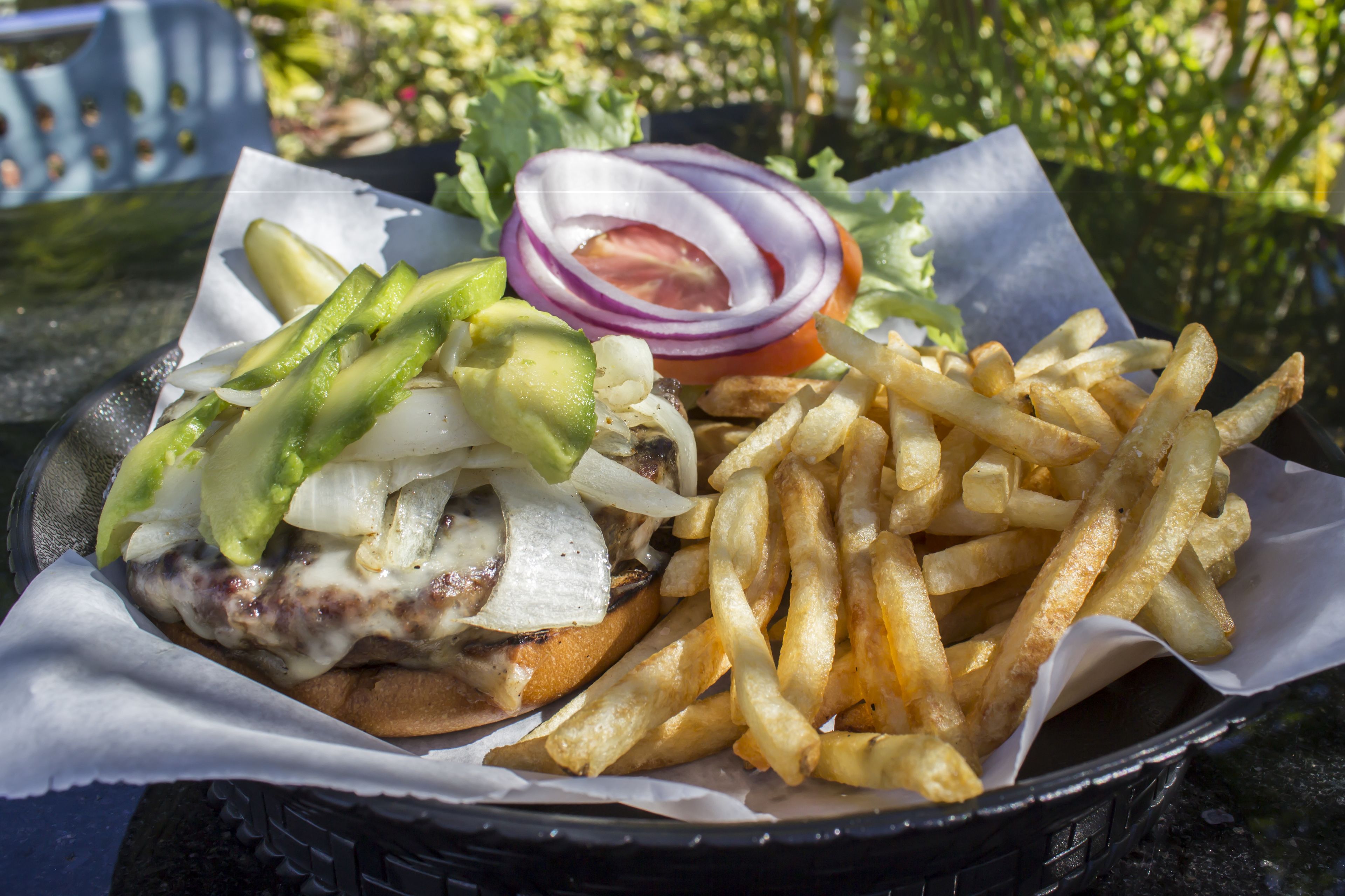 A meal consisting of a burger with cheese, pickles, onions, and a slice of tomato, accompanied by a side of French fries.