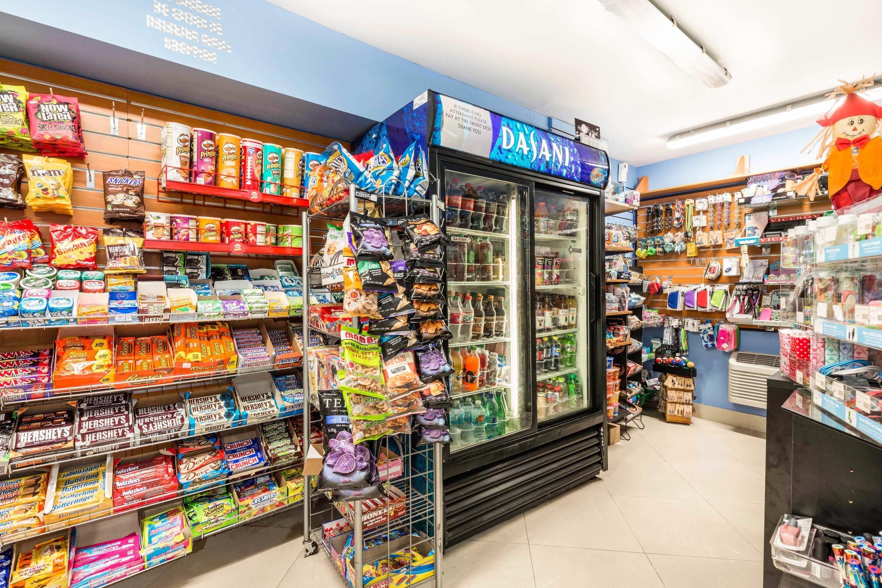 Una tienda de dulces con estantes llenos de caramelos y una vitrina refrigerada.