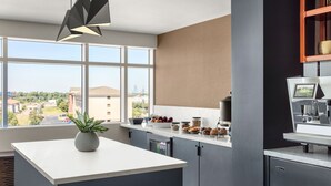 A modern kitchen with a large window, a central island, and a coffee machine. - Delta Hotels by Marriott Midwest City at the Reed Conference Center (Midwest City)