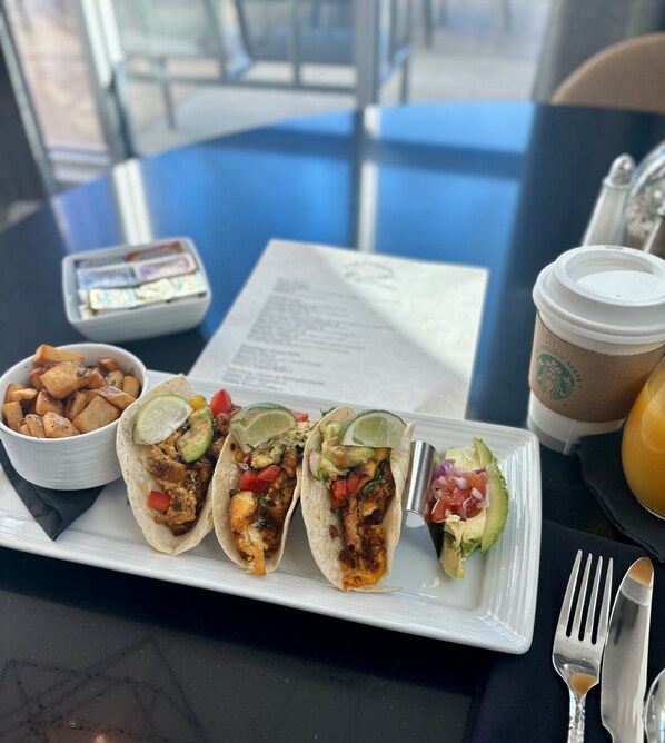 A table with a plate of tacos, a bowl of potato wedges, a cup of coffee, and a menu. - Delta Hotels by Marriott Midwest City at the Reed Conference Center (Midwest City)
