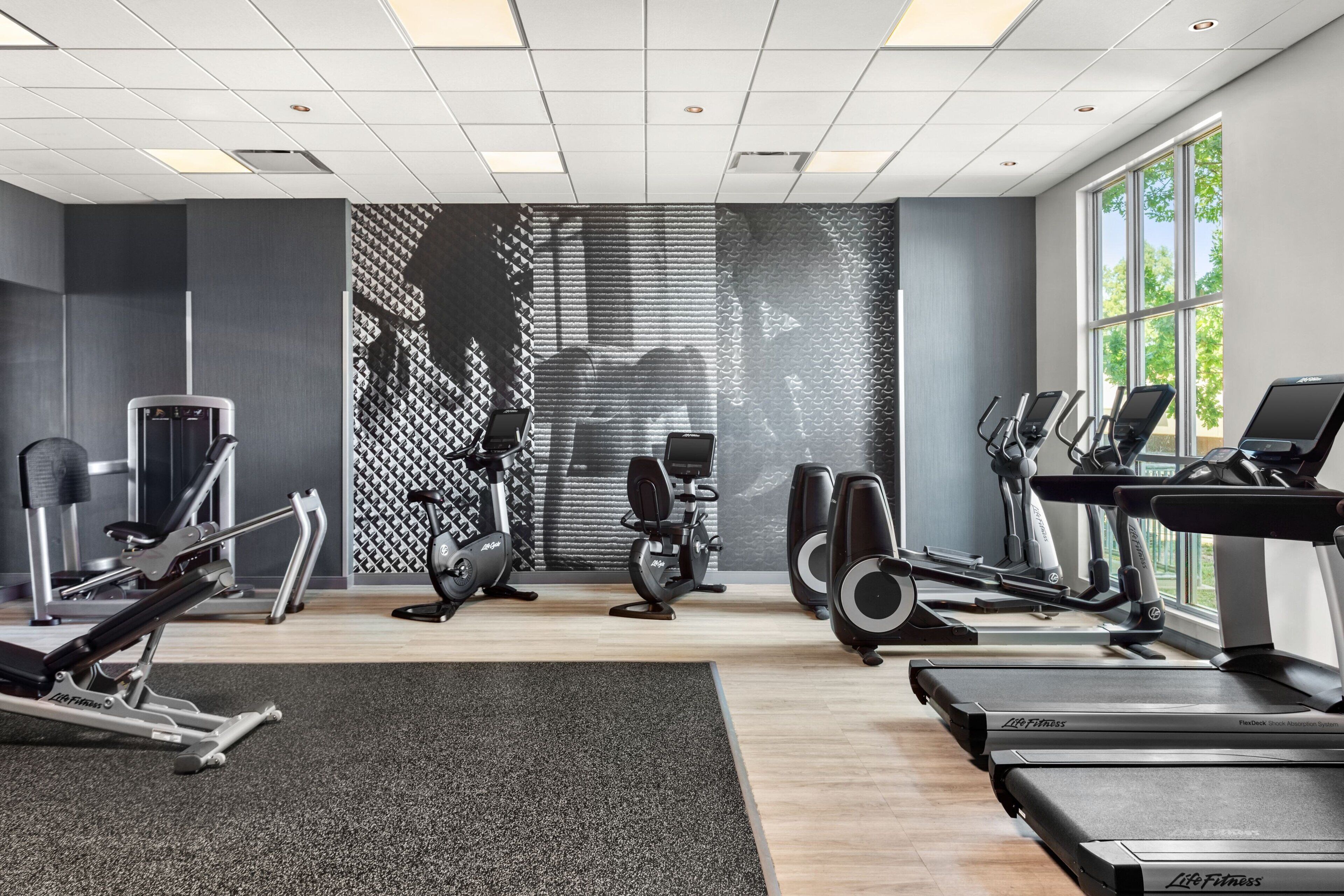 Une salle de sport équipée de tapis de course, de vélos elliptiques et de matériel de musculation.