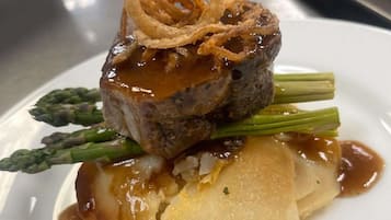 Un plato con filete, espárragos y patata.