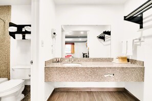 A modern bathroom with a granite countertop, a white sink, and a mirror.