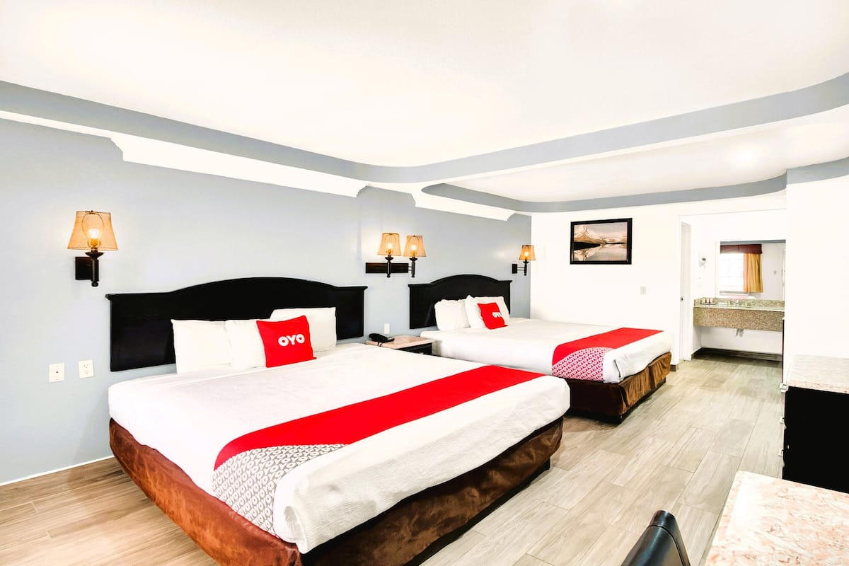 A hotel room with two beds, each with a red and white bedspread, and a small desk with a chair.