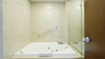 A modern bathroom with a glass shower enclosure, a white bathtub, and a wooden door.