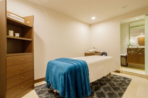 Une chambre à coucher avec un lit, une commode en bois, une table de chevet et une salle de bain visible à travers une porte ouverte.
