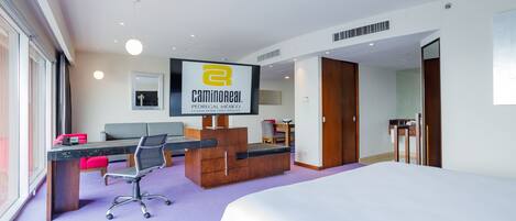 Une chambre d’hôtel avec un lit, un bureau avec un ordinateur, une chaise et un téléviseur.